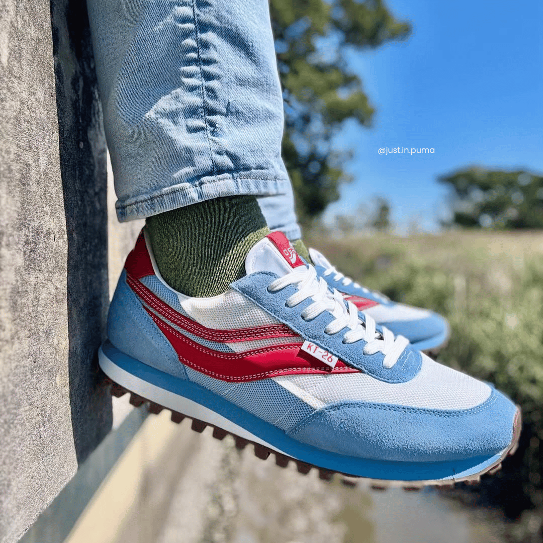 Blue and red sneakers worn with light blue jeans against a natural background