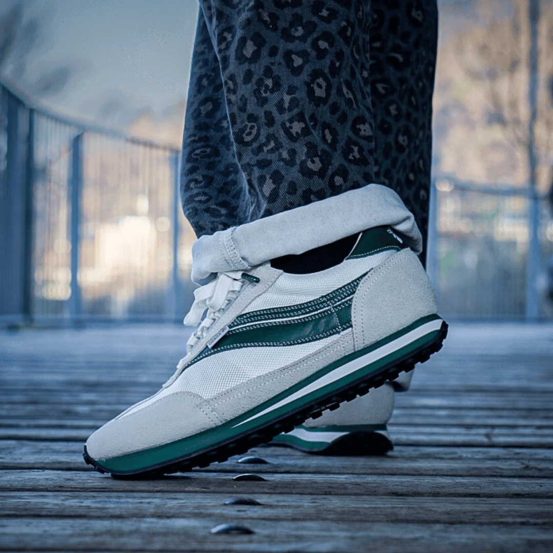 White and green sneaker worn by a person with leopard print pants outdoors.