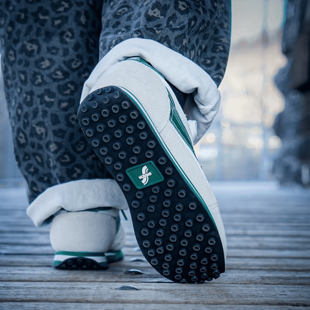 Close-up of a shoe with a green logo on the bottom of a rubber sole