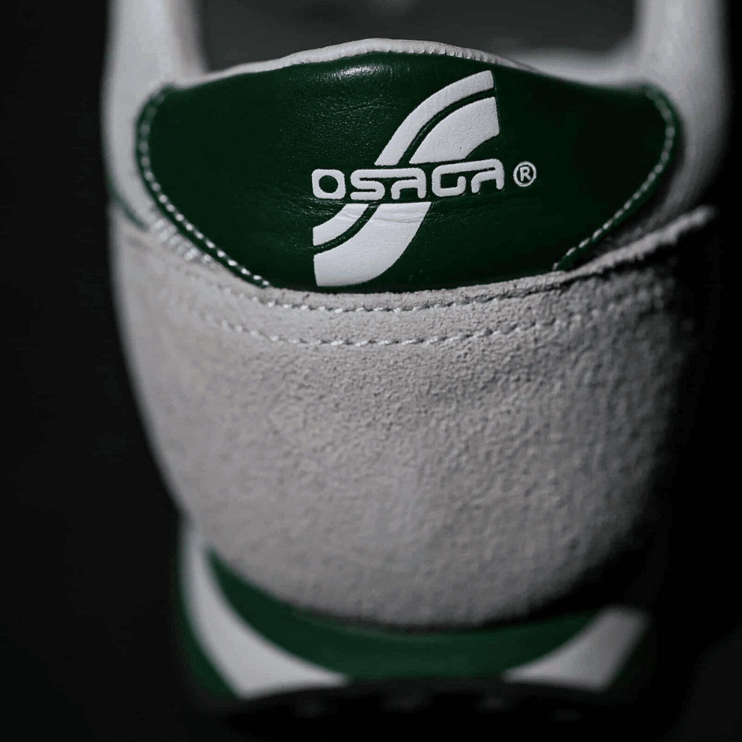 Close-up of a green and white Osaga logo on the back of a sneaker.