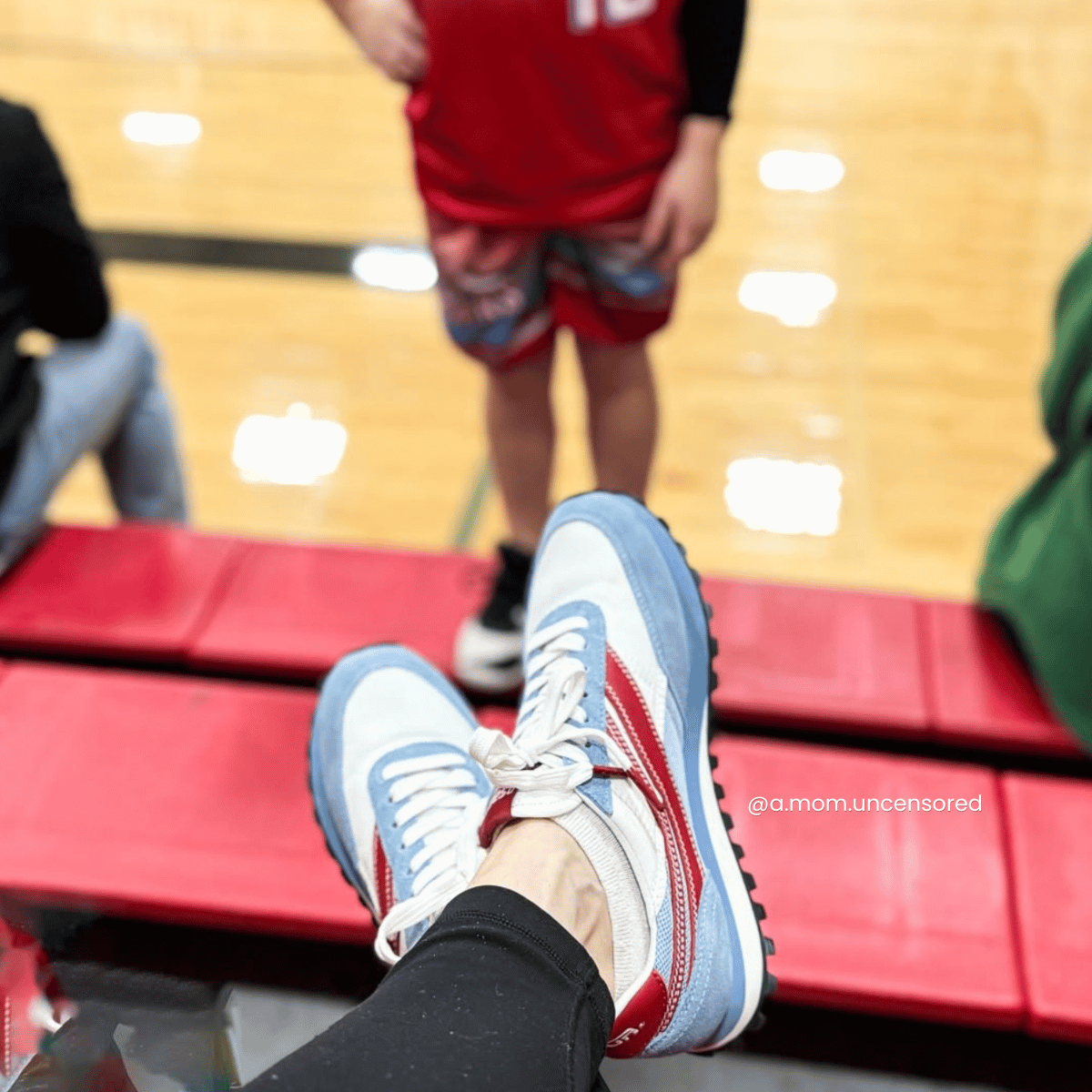 Person wearing red and white sneakers with a basketball player in the background on a court.