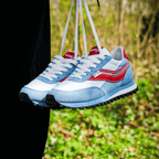 Blue and red retro sneakers with white laces hanging outdoors.