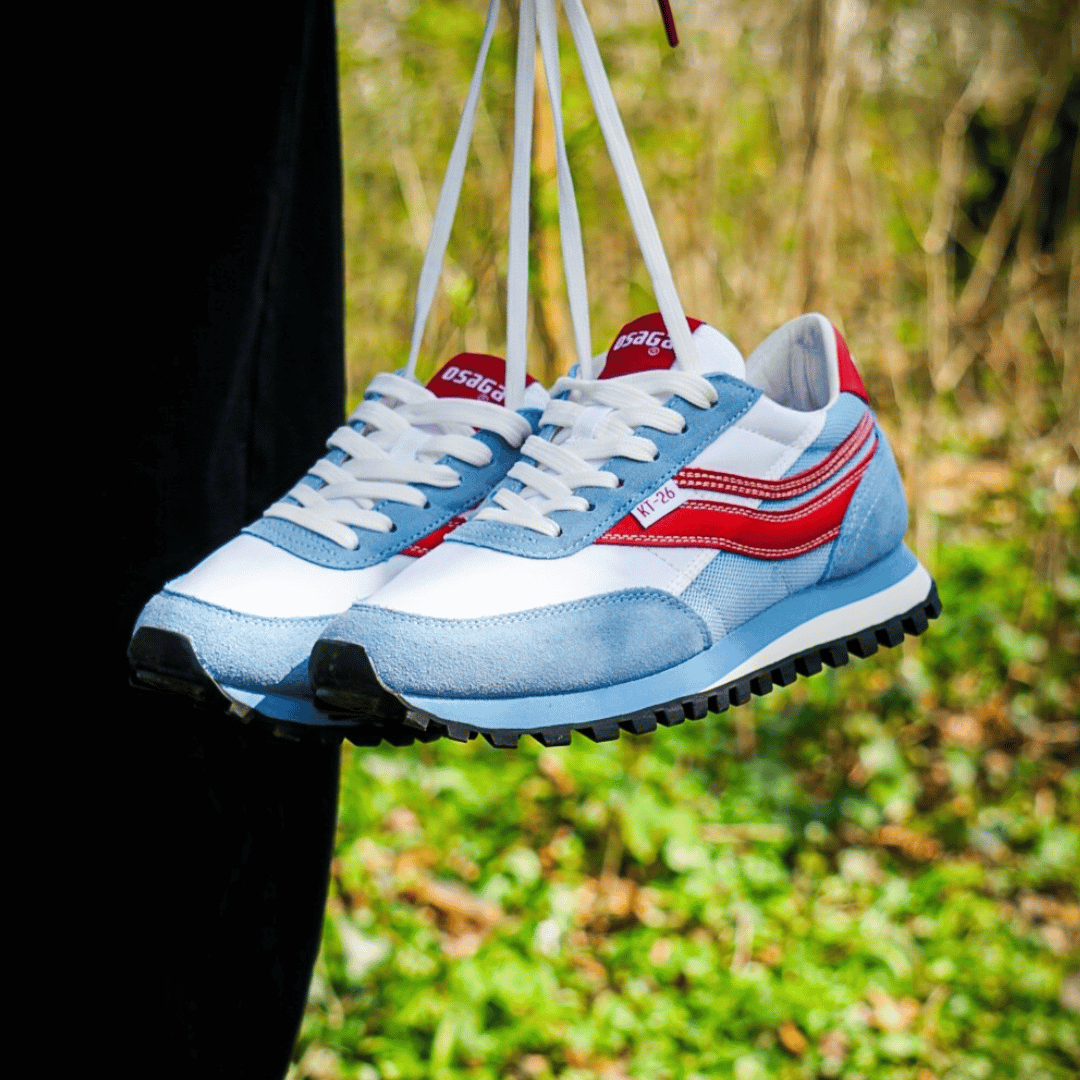 Blue and red retro sneakers with white laces hanging outdoors.